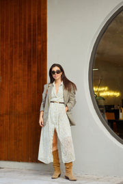 Woman in a stylish outfit standing in front of a modern building entrance.